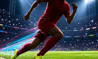 Futbolista corriendo a máxima velocidad por la banda de un estadio nocturno con efecto de desenfoque de movimiento