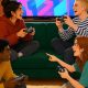 Cuatro amigos jugando juntos a videojuegos cooperativos en un salon