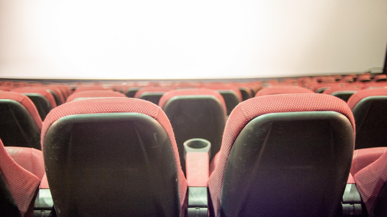 Sala de cine con butacas rojas y pantalla iluminada