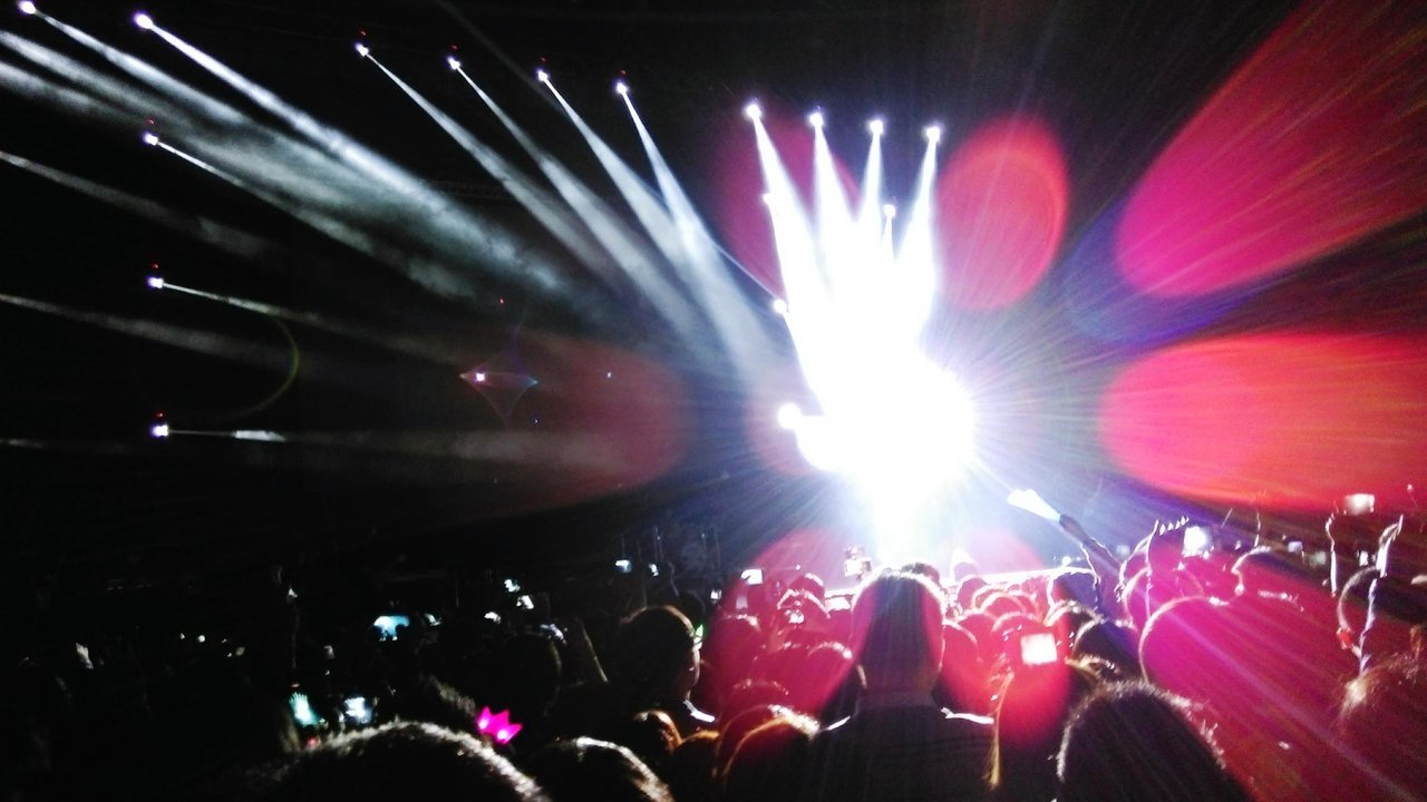 Gente disfrutando de un concierto multitudinario con luces de escenario