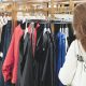 Perchas con ropa en una tienda de moda — las colecciones de diseñador en H&M se agotan en horas