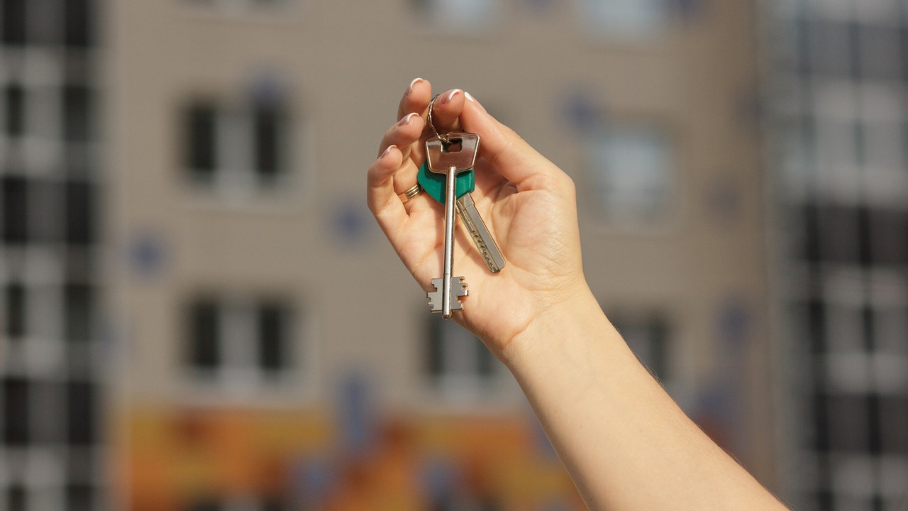 Chica sosteniendo las llaves de primer plano de apartamento nuevo, fondo borroso