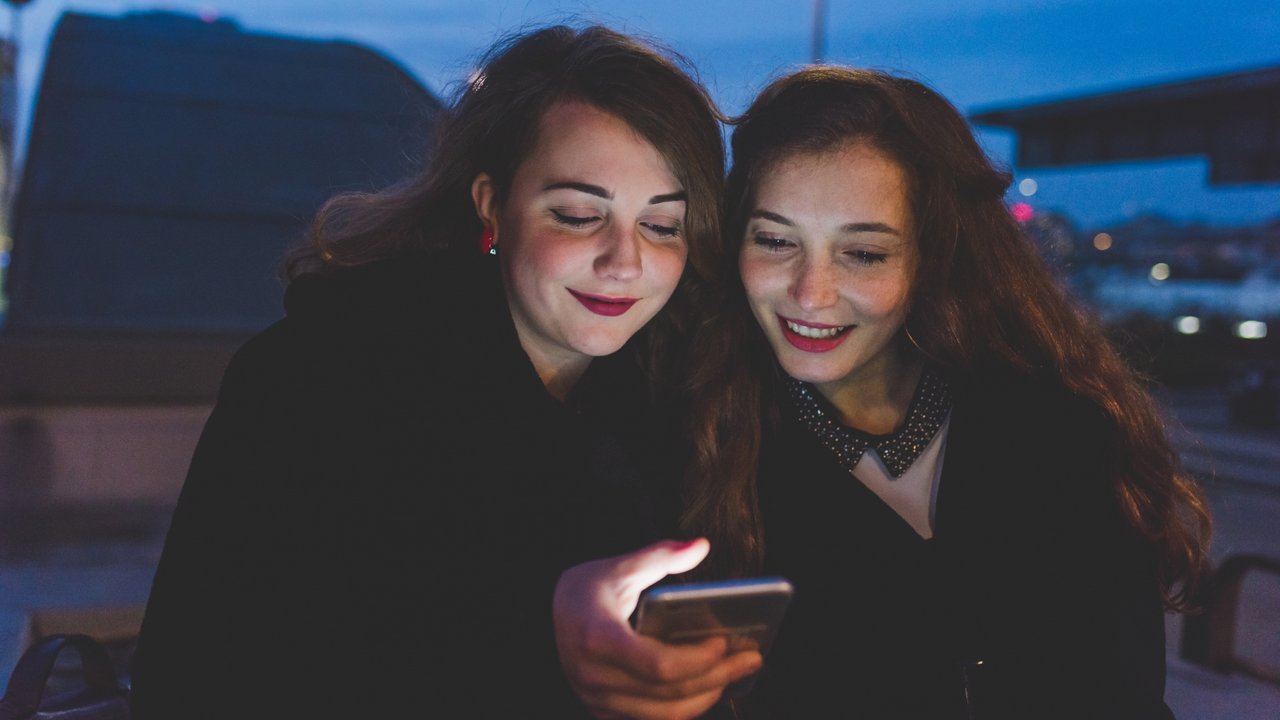 Jóvenes con móviles de noche en una calle urbana durante disturbios convocados por redes sociales